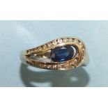 A sapphire and diamond ring set an oval sapphire within a loop of graduated brilliant cut diamonds