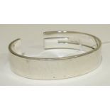 A Gucci silver bangle in the form of a stylised "G", marked "Gucci, Made in Italy", (remaining marks