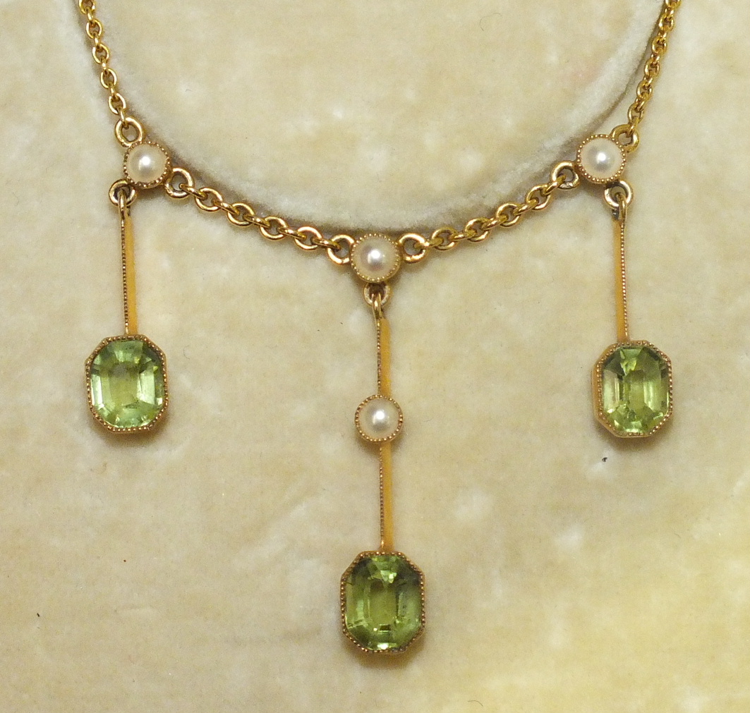 An Edwardian peridot and pearl fringe necklace, the three graduated drops set step cut peridots