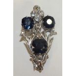 A sapphire and diamond brooch of symmetrical design, claw set three round cut sapphires of approx