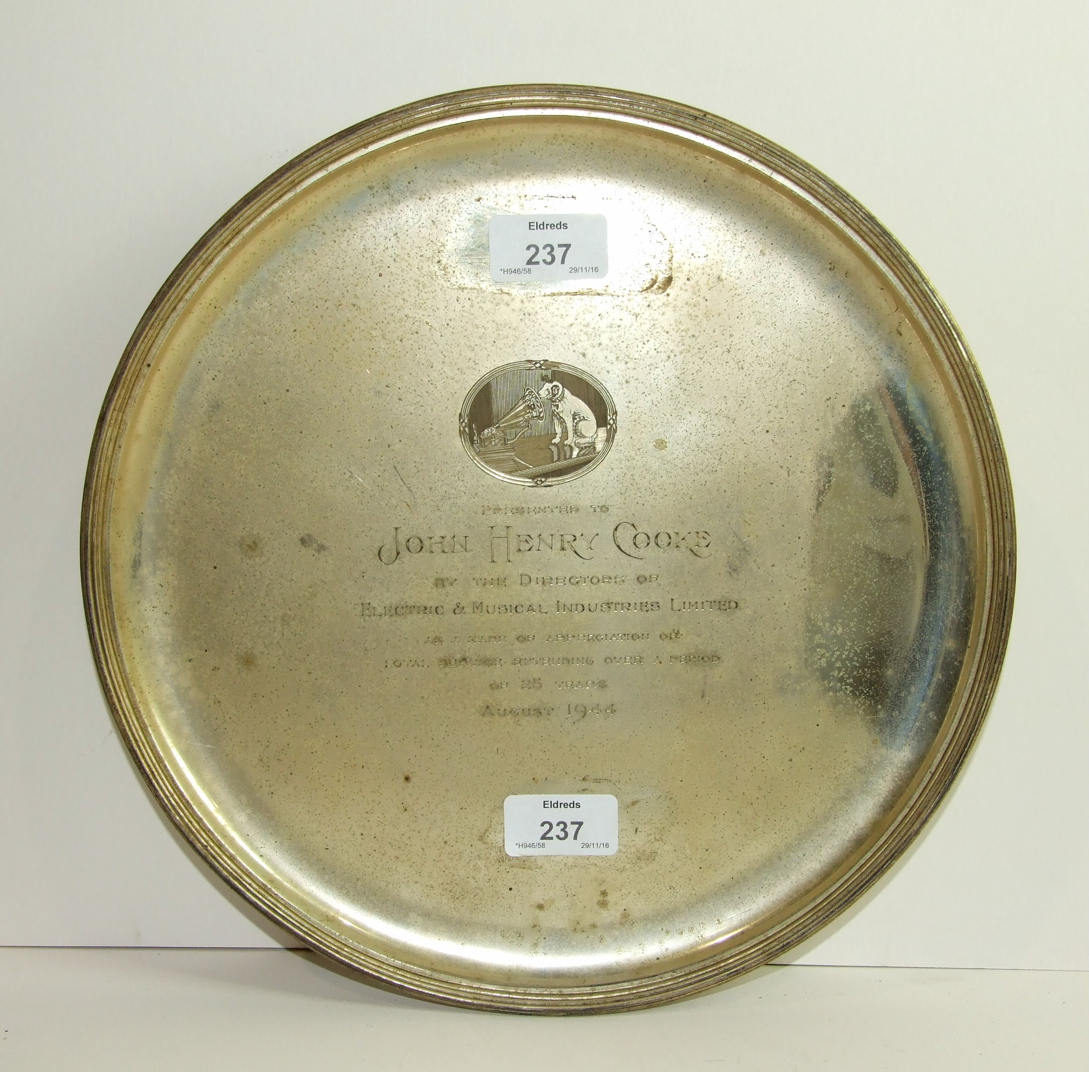 A silver circular salver with reeded rim on three scroll feet, with engraved "His Master's Voice"