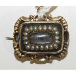 An early-19th century mourning brooch, the rectangular hair locket within a border of pearls and