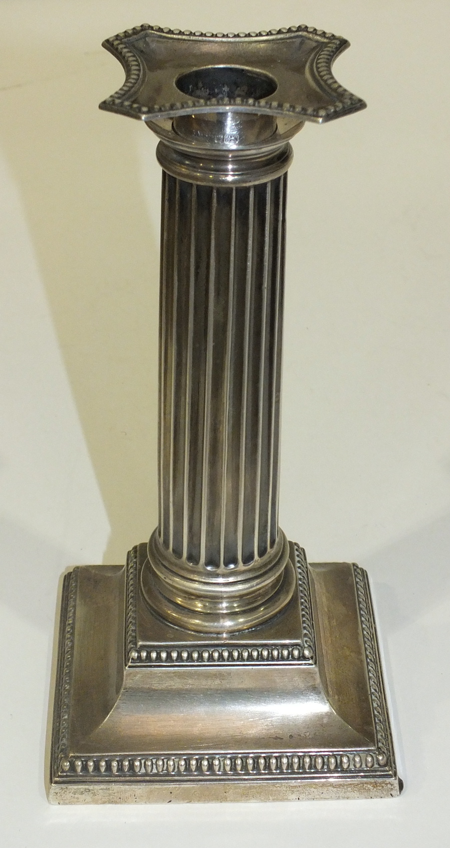 A silver Doric column candlestick with beaded base, Sheffield 1911, 18cm high.