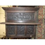 An antique oak sideboard back, the panels carved with a procession of figures, 102cm wide, 92cm