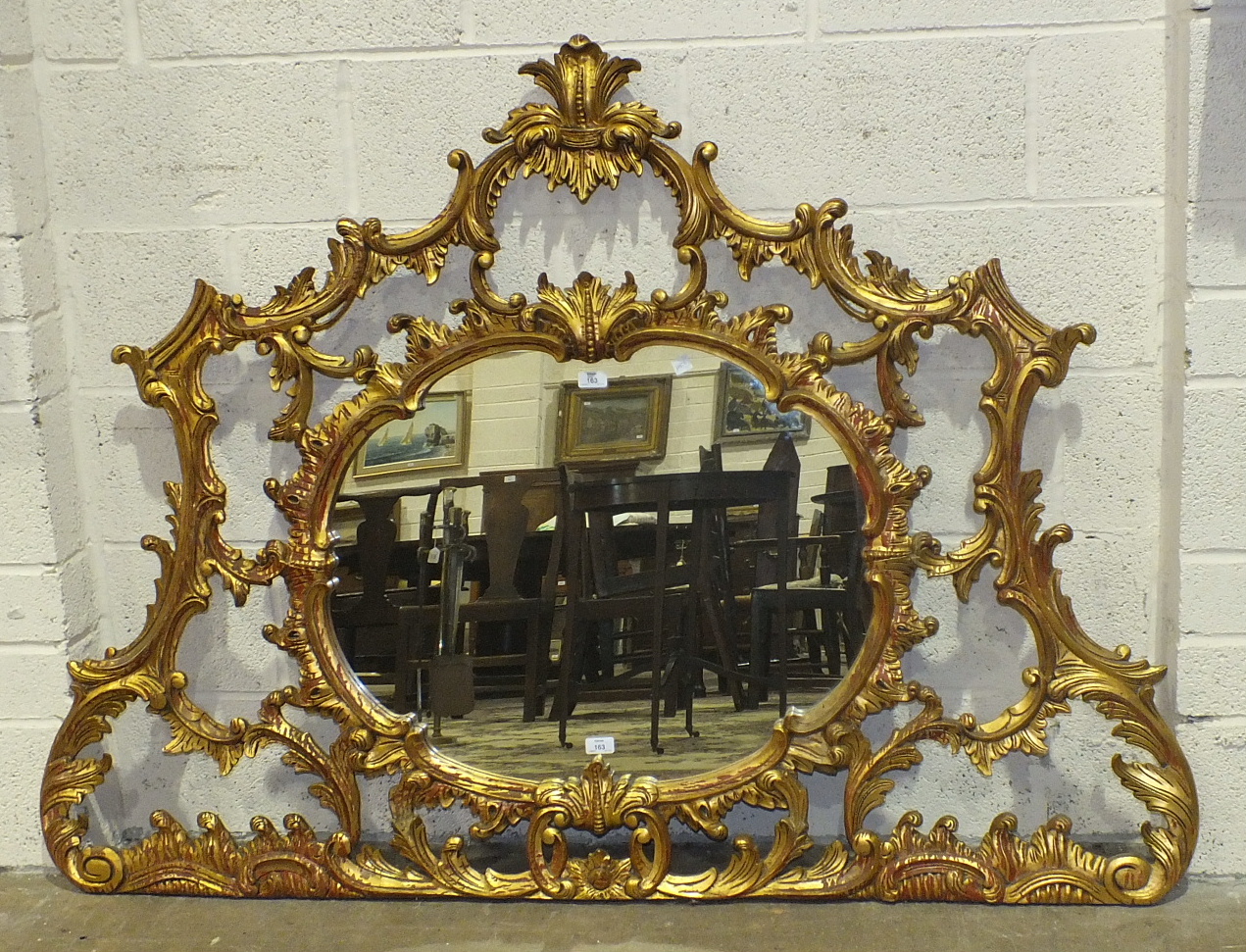 A reproduction rococo gilt wood wall mirror, the pierced scrolling frame around a central oval