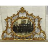 A reproduction rococo gilt wood wall mirror, the pierced scrolling frame around a central oval