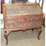 A Continental carved oak bureau, the fall front above two drawers, on stand with cabriole front