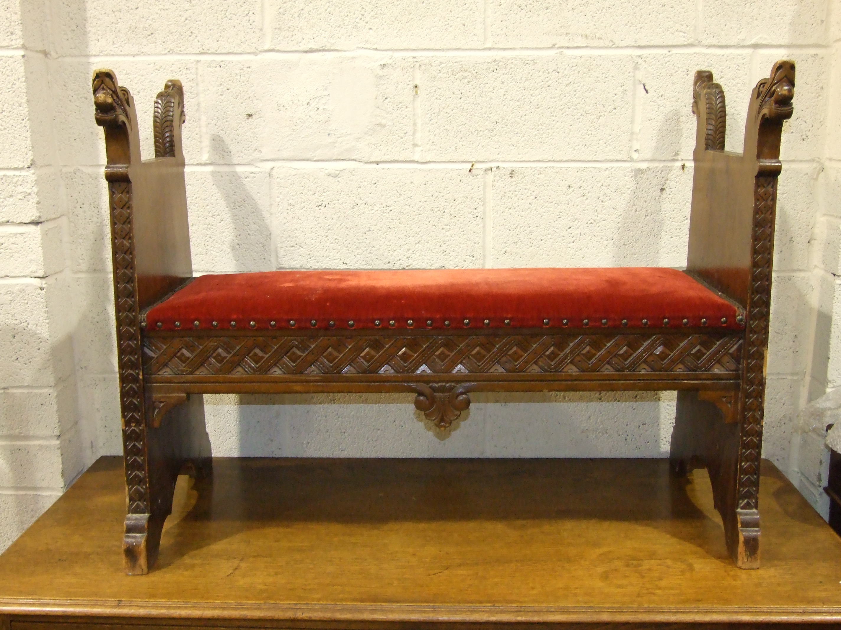 A Scandinavian stained wood hall seat, the ends carved as mythical beasts, 113cm.
