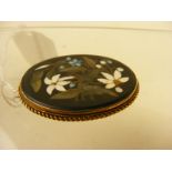 An oval framed yellow metal brooch set with pietra dura floral spray (examine)