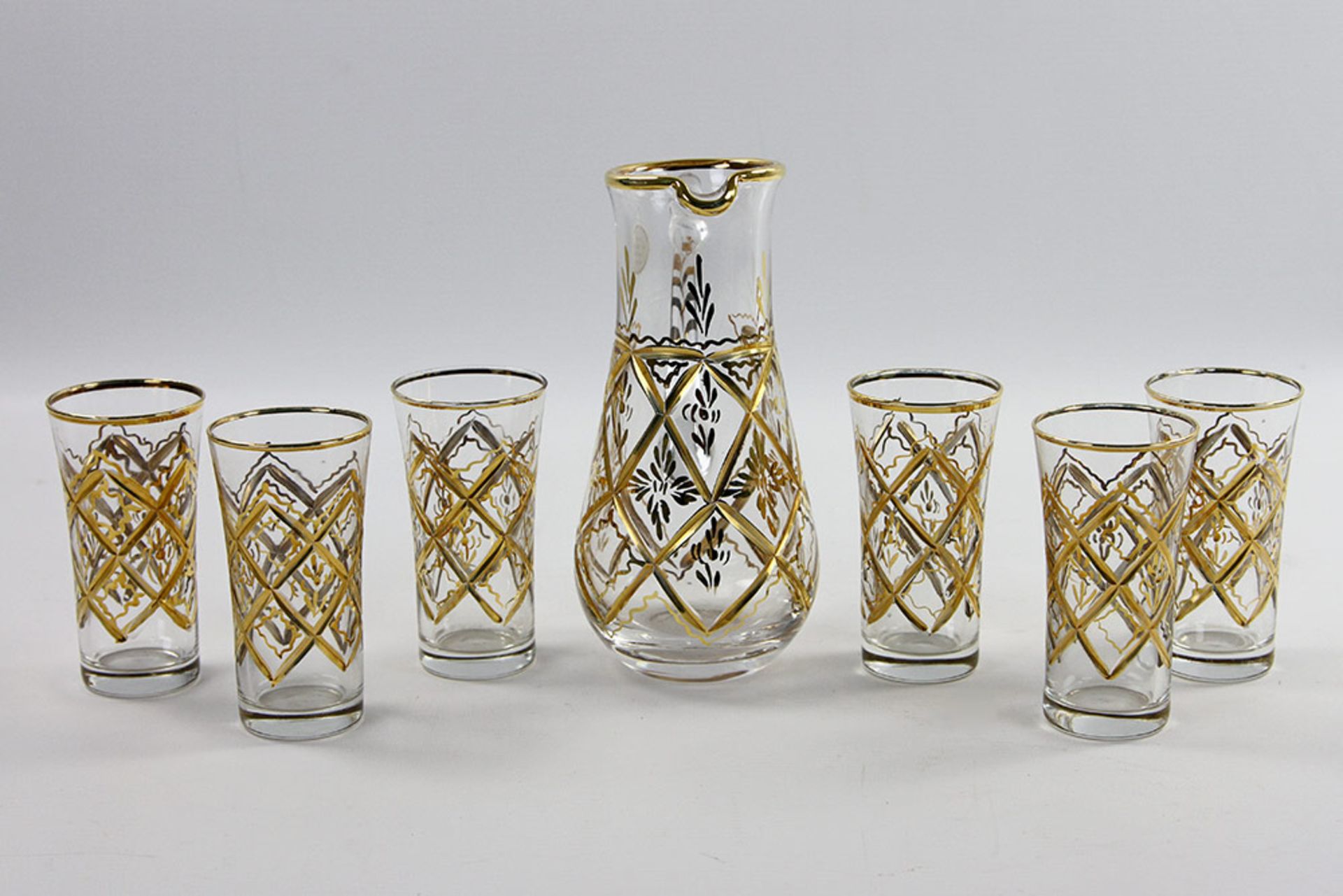 Kleine Henkelkanne mit 6 Gläschen, 20. Jh. Farbloses Glas mit Schliff- und Golddekor. Kanne H. ca.