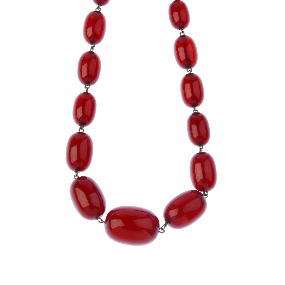 A red plastic bead necklace. Comprising thirty-two graduated oval-shape plastic beads, measuring 2.2