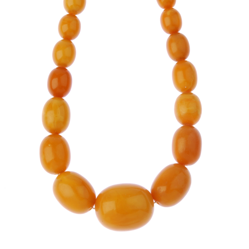 A natural amber bead necklace. Designed as a single row of forty-nine graduated oval-shape natural