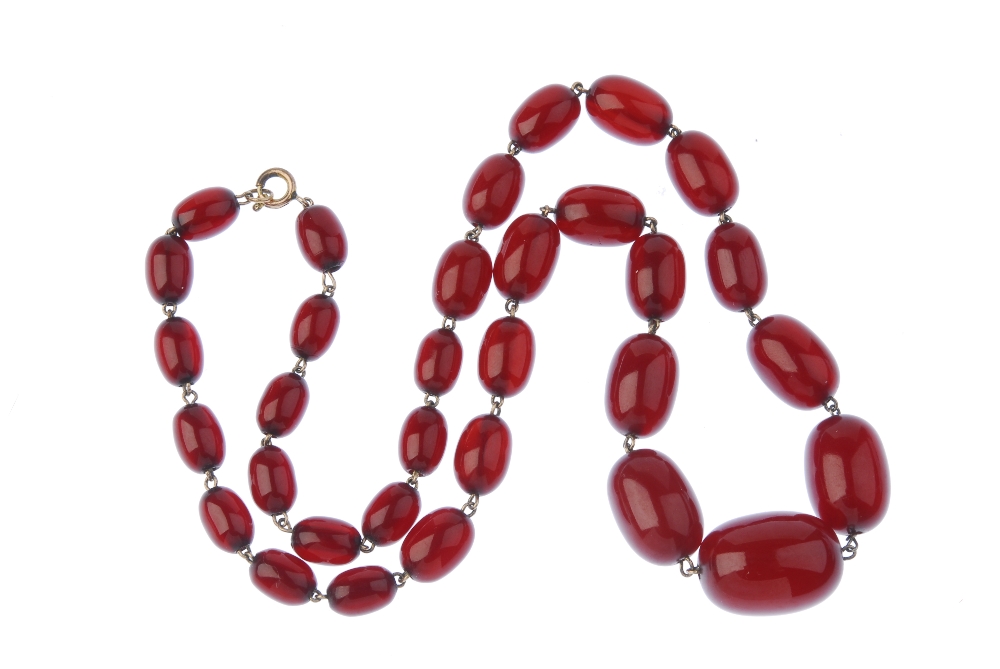 A red plastic bead necklace. Comprising thirty-two graduated oval-shape plastic beads, measuring 2.2 - Image 2 of 2