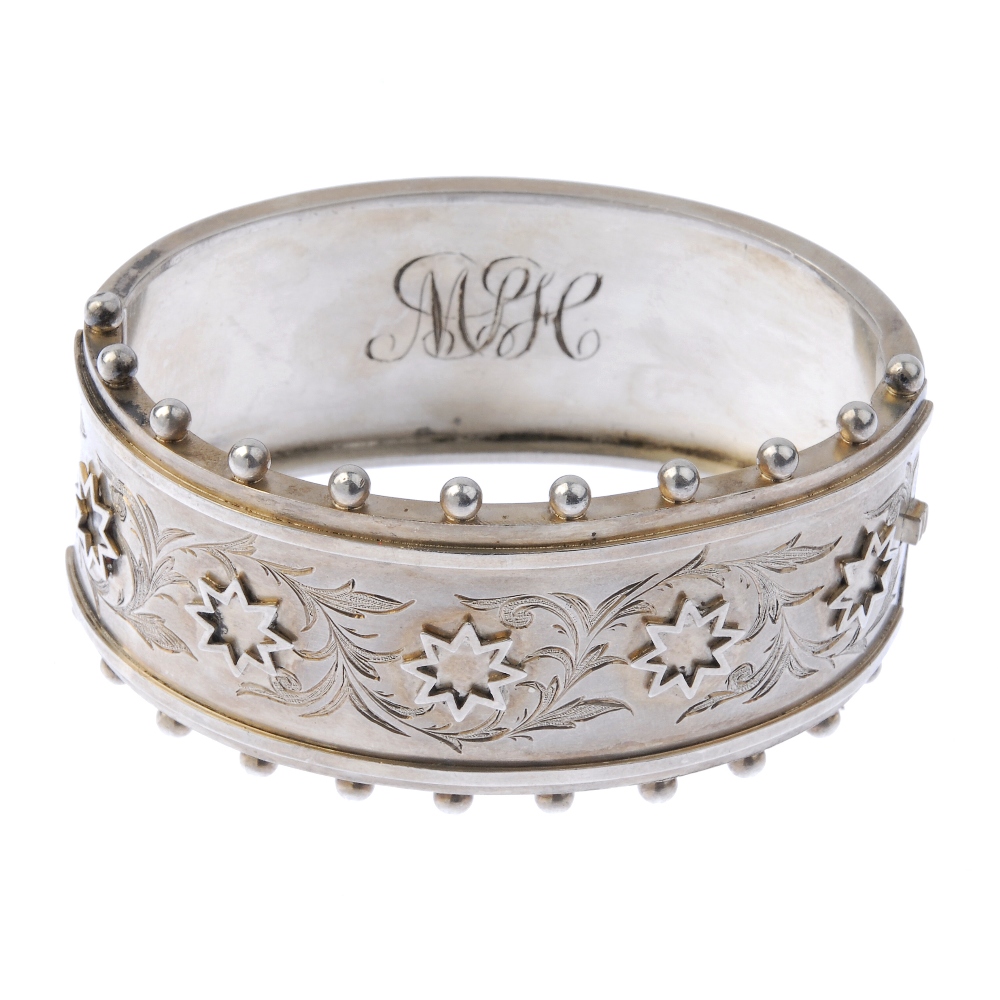 Three silver bangles and a napkin ring. To include one with applied stars and foliate engraving to