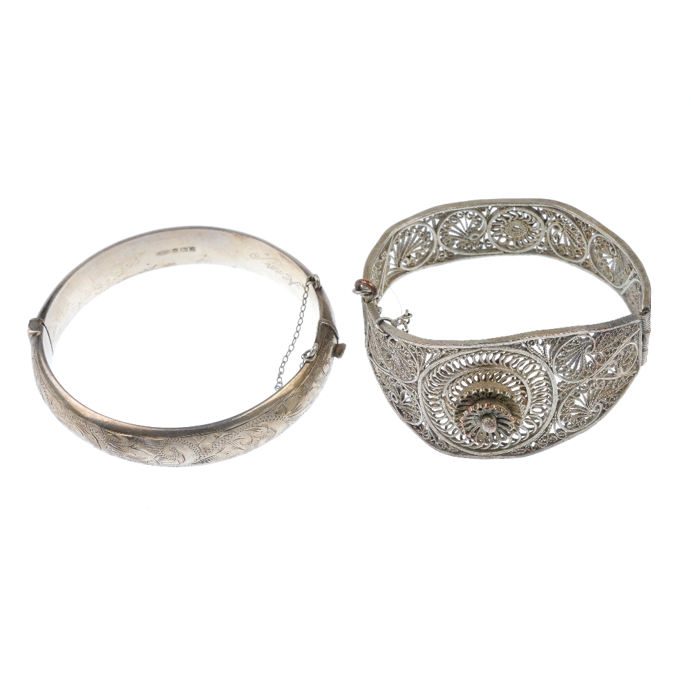 A selection of bangles. To include a hinged filigree bangle with flower detail and an