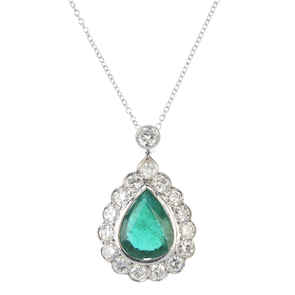 An emerald and diamond pendant. The pear-shape emerald collet, within a circular-cut diamond