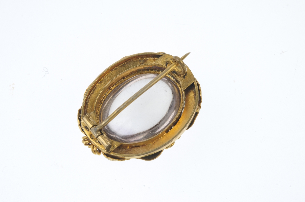 A late 19th century gold rock crystal brooch. The oval rock crystal cabochon, within a textured, - Image 2 of 2