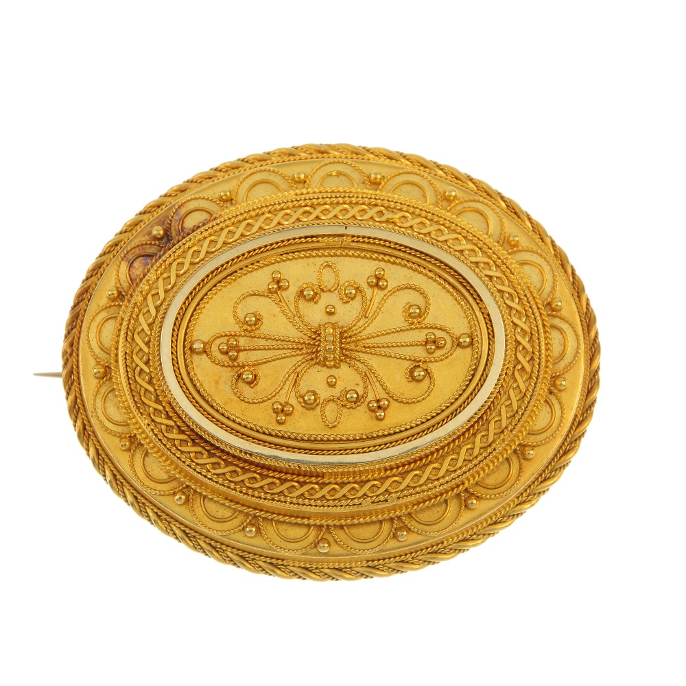 A late 19th century gold brooch. Of oval outline, the scrolling cannetille panel, within a stepped