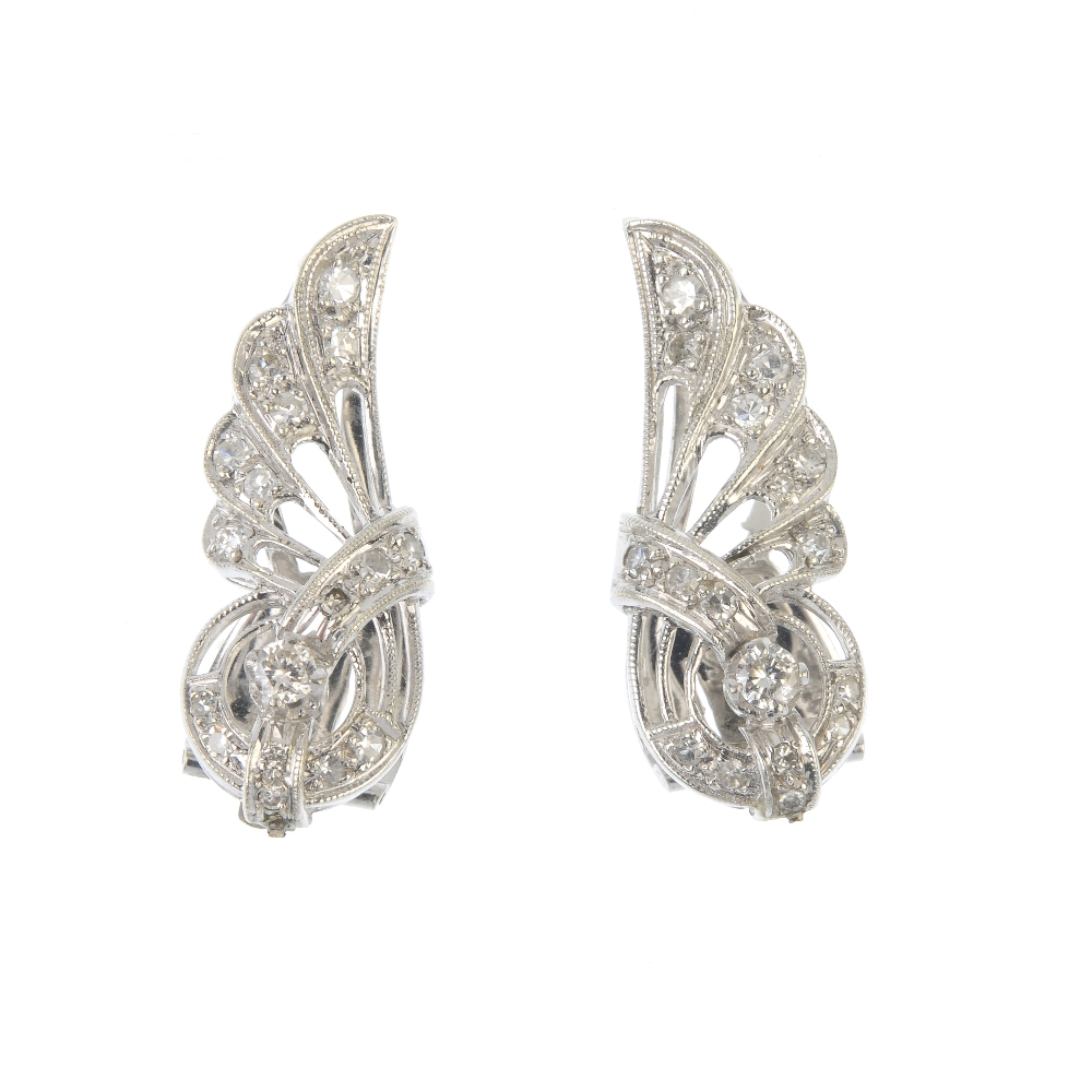 A pair of mid 20th century diamond ear clips. Each of openwork design, the stylised wing, set