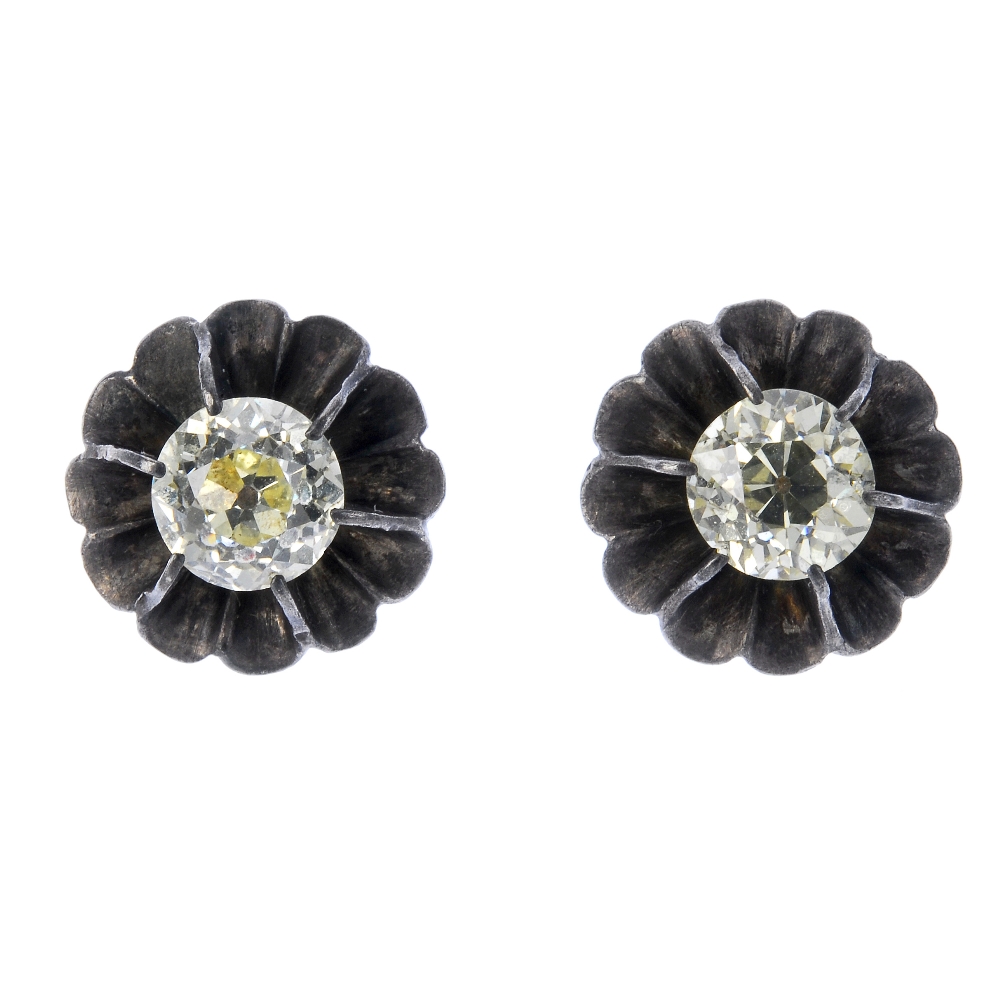A pair of diamond ear studs. Each designed as an old-cut diamond, within a scalloped surround.