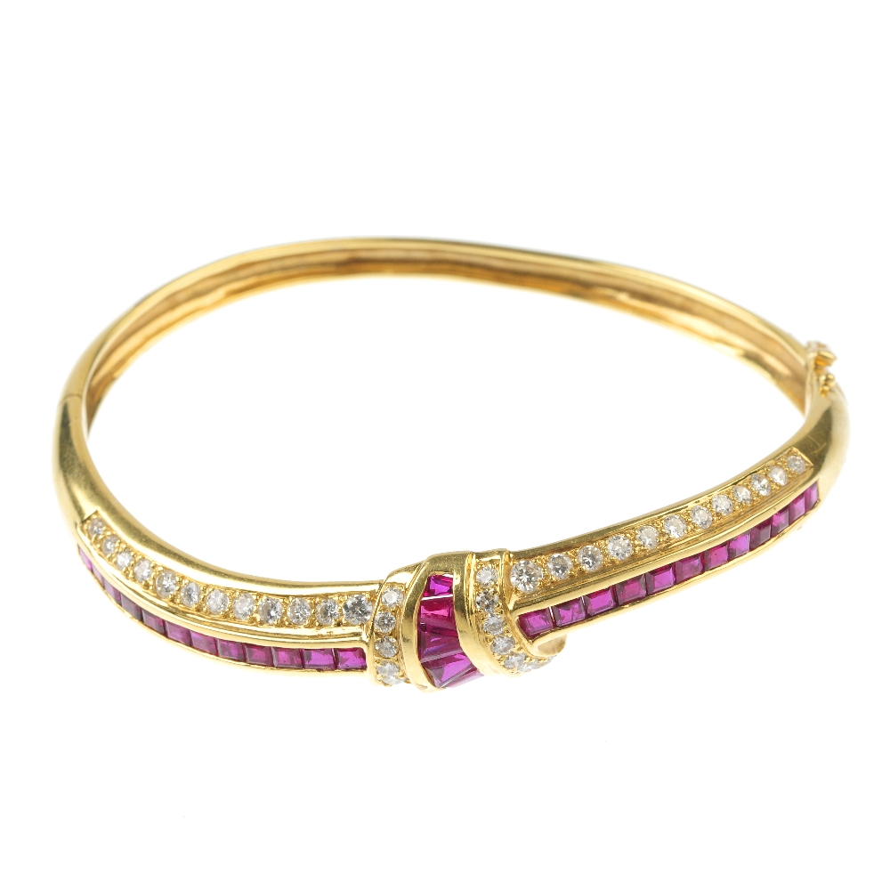 A ruby and diamond hinged bangle. The front designed as a series of calibre-cut ruby and pave-set