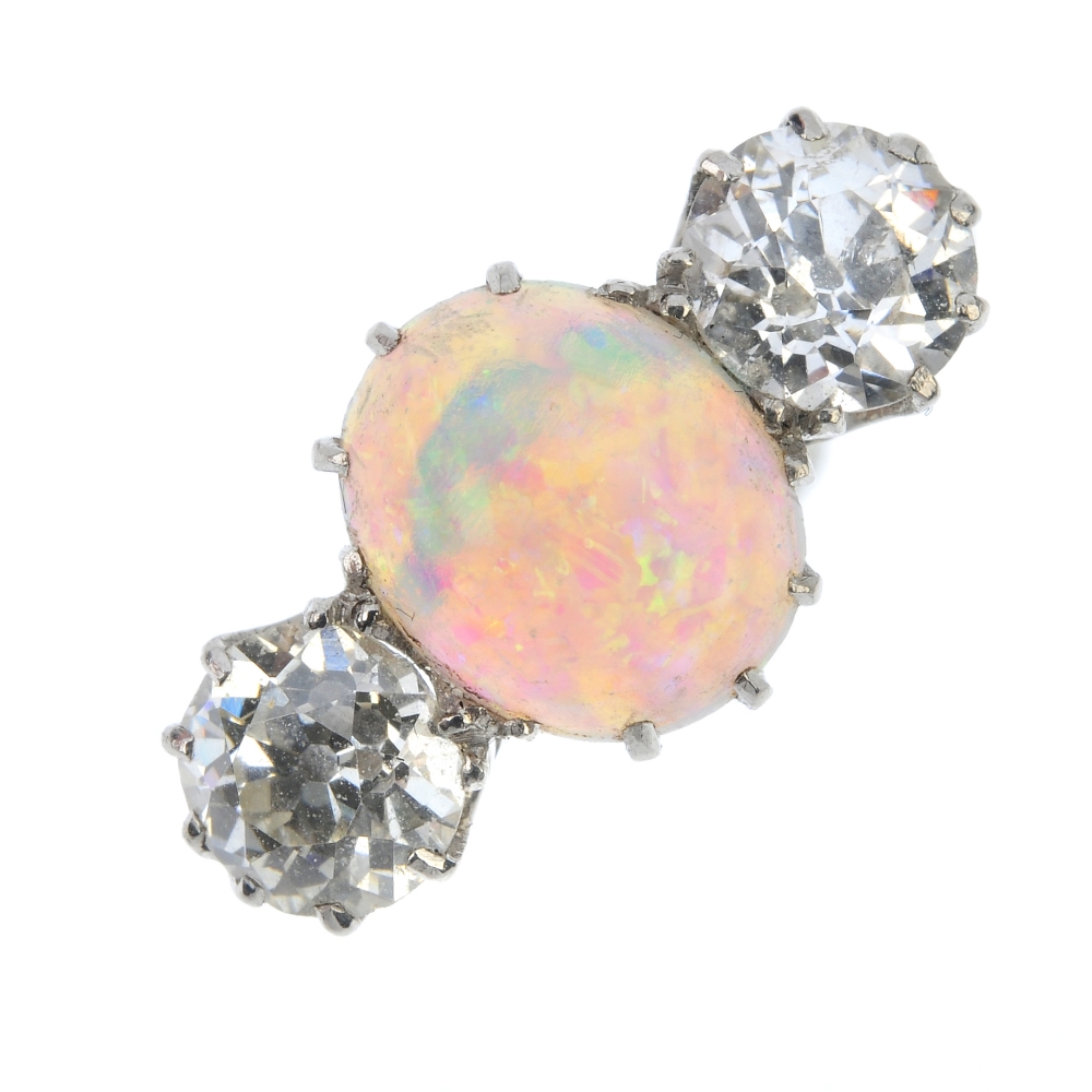 An opal and diamond three-stone ring. The oval opal cabochon, with circular-cut diamond sides, to