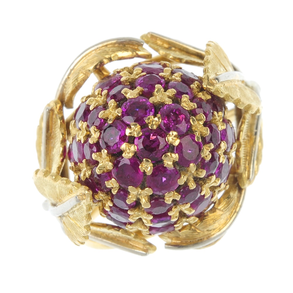 A 1950s 18ct gold ruby dress ring. The pave-set ruby bombe panel, within a bi-colour, textured