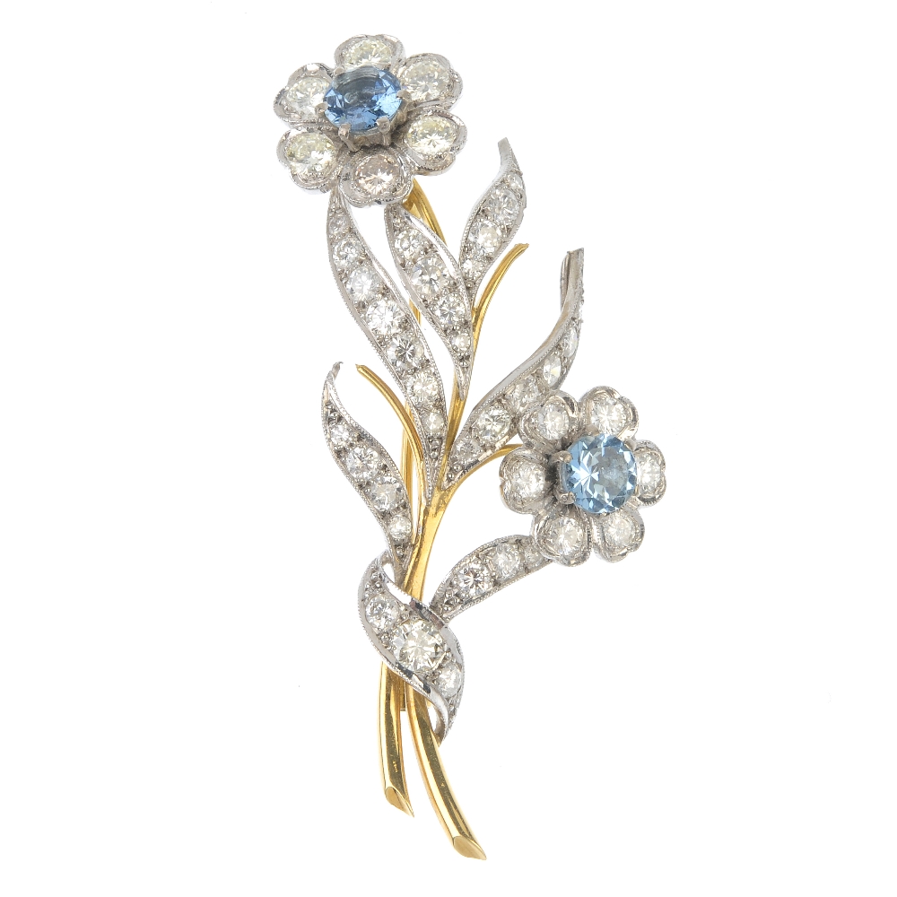 An aquamarine and diamond floral spray brooch. The circular-shape aquamarine and brilliant-cut