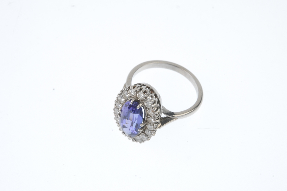 An 18ct gold tanzanite and diamond cluster ring. The oval-shape tanzanite, within a brilliant-cut - Image 2 of 3