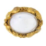A late 19th century gold rock crystal brooch. The oval rock crystal cabochon, within a textured,