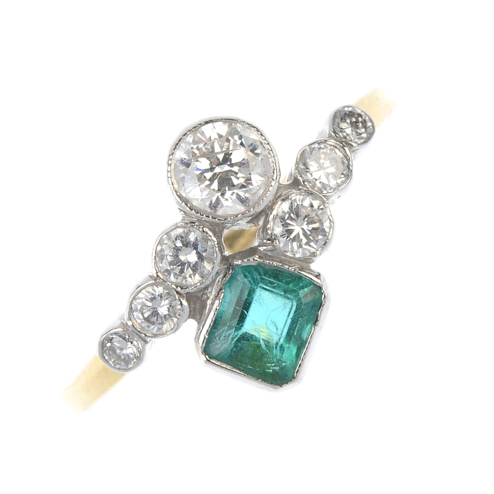 An emerald and diamond dress ring. Designed as two graduated brilliant-cut diamond crossover