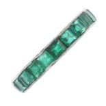 An emerald full-circle eternity ring. The square-shape emerald line, with scrolling engraved