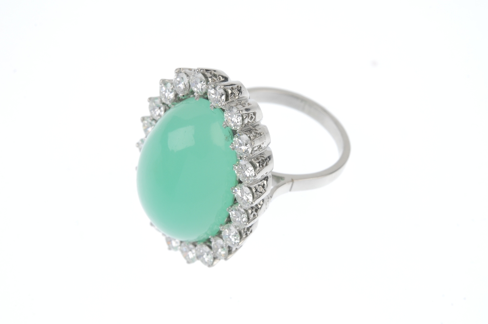 A jade and diamond cluster ring. The oval jade cabochon, within a brilliant-cut diamond surround, to - Image 2 of 3