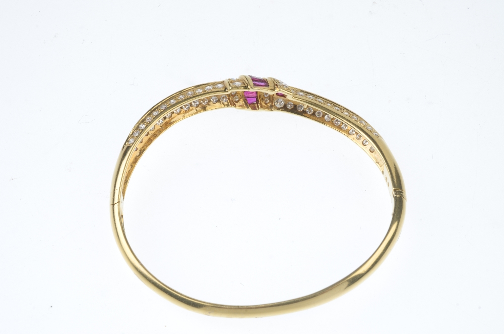A ruby and diamond hinged bangle. The front designed as a series of calibre-cut ruby and pave-set - Image 2 of 2