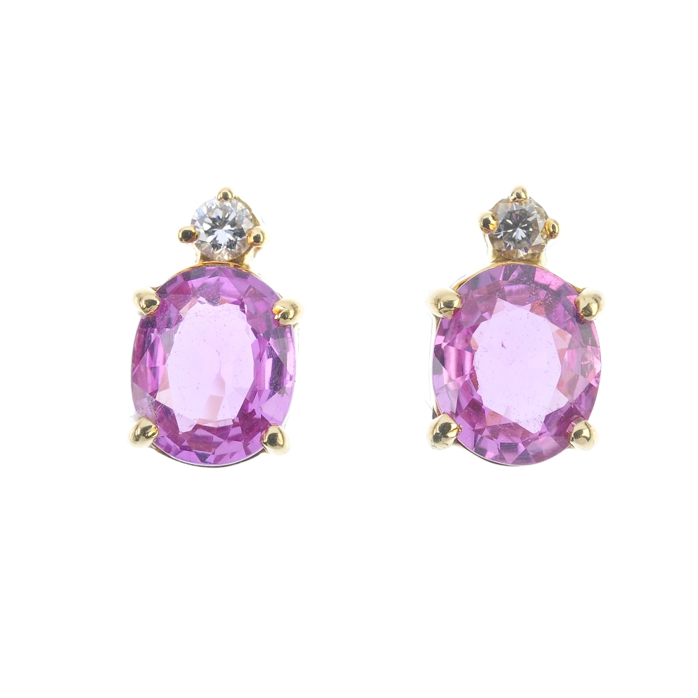A pair of sapphire and diamond ear studs. Each designed as an oval-shape pink sapphire, with a