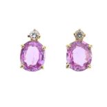 A pair of sapphire and diamond ear studs. Each designed as an oval-shape pink sapphire, with a
