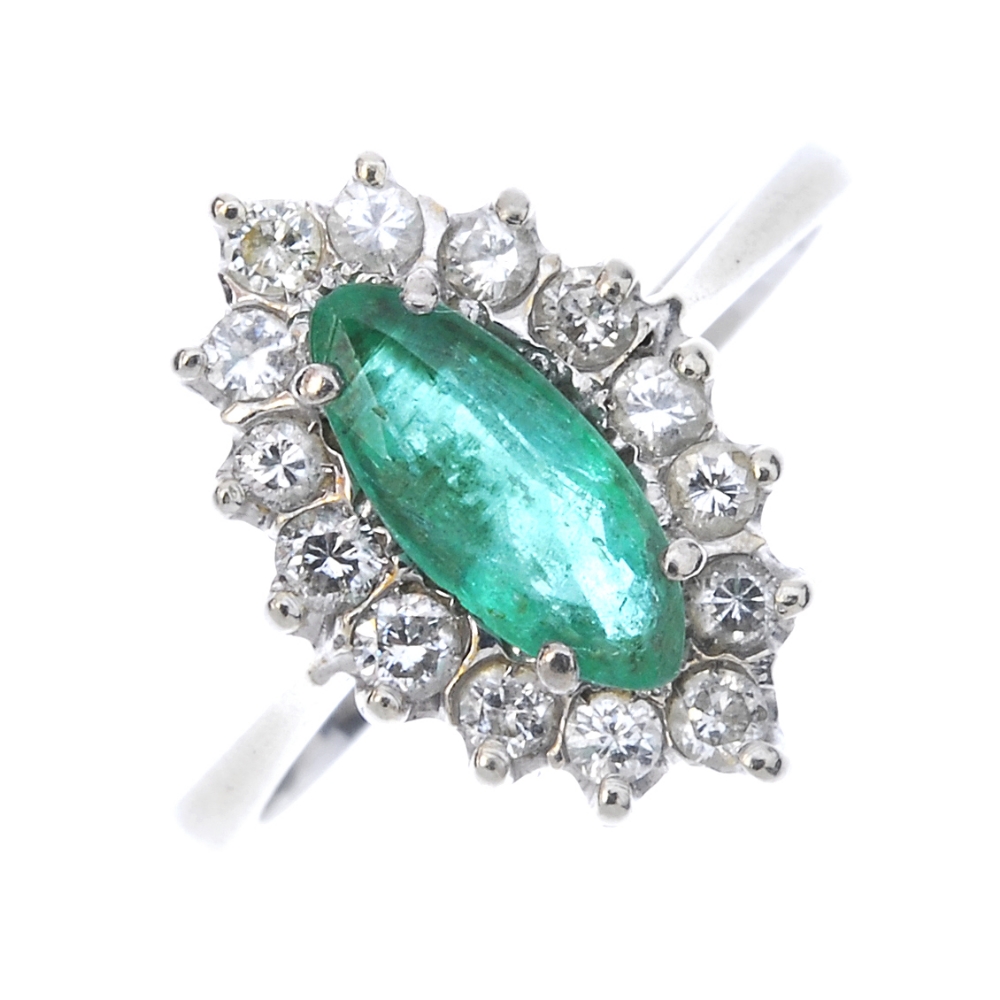 An emerald and diamond cluster ring. The marquise-shape emerald, within a brilliant-cut diamond