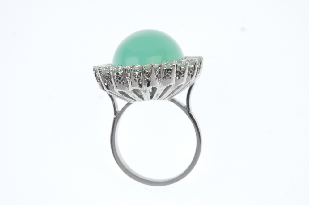 A jade and diamond cluster ring. The oval jade cabochon, within a brilliant-cut diamond surround, to - Image 3 of 3