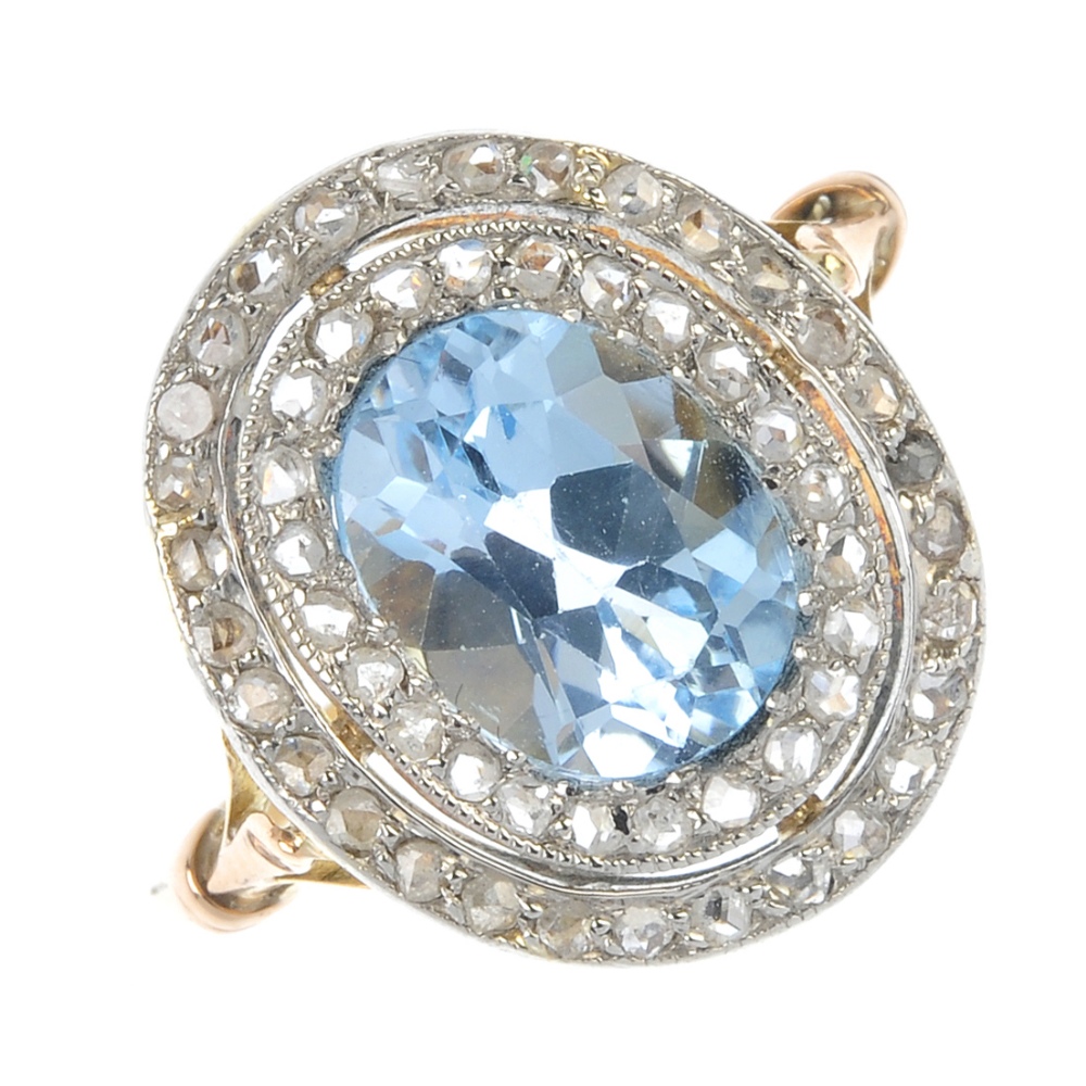 An early 20th century platinum and 18ct gold topaz and diamond cluster ring. The replacement oval-
