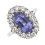 An 18ct gold tanzanite and diamond cluster ring. The oval-shape tanzanite, within a brilliant-cut