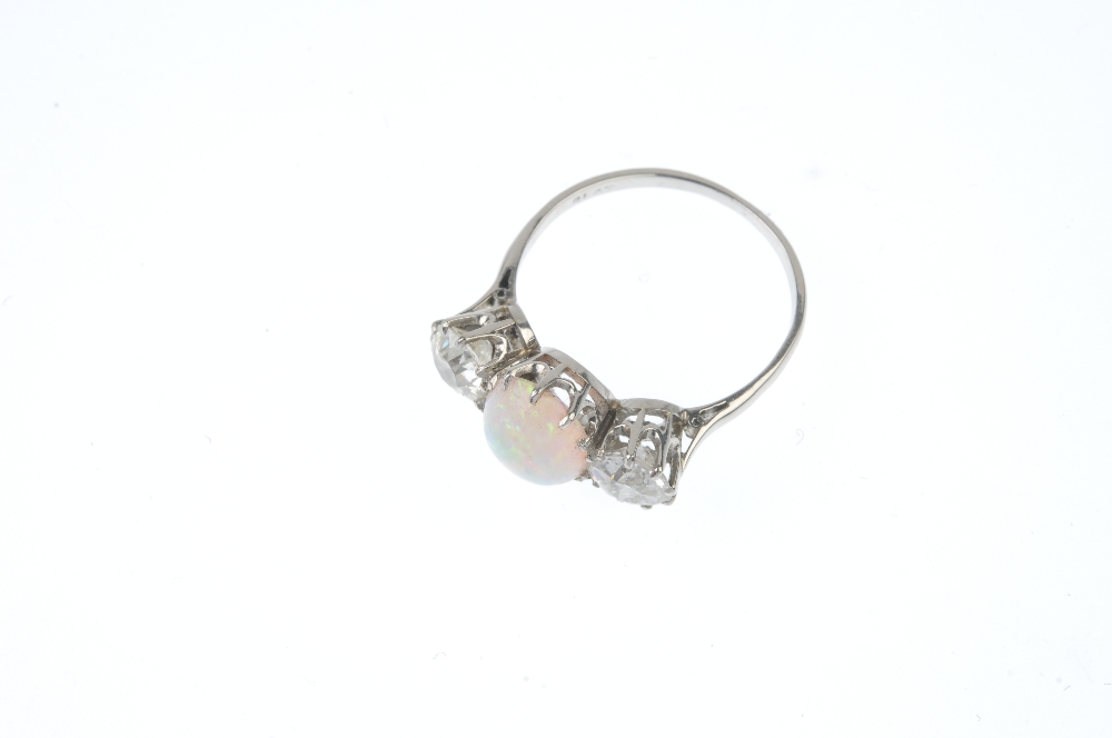 An opal and diamond three-stone ring. The oval opal cabochon, with circular-cut diamond sides, to - Image 2 of 3