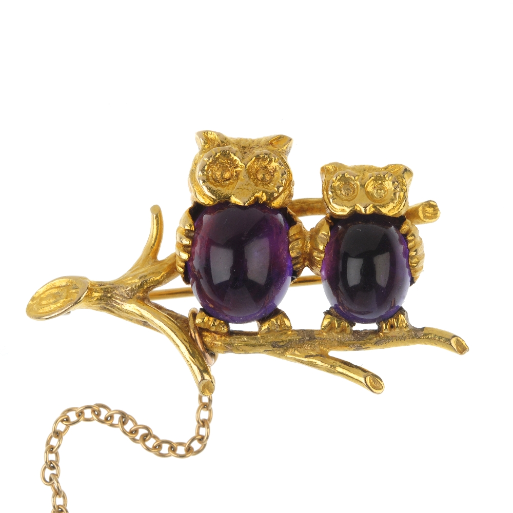 A 9ct gold amethyst owl brooch. Designed as two owls, with oval amethyst cabochon bodies, perched