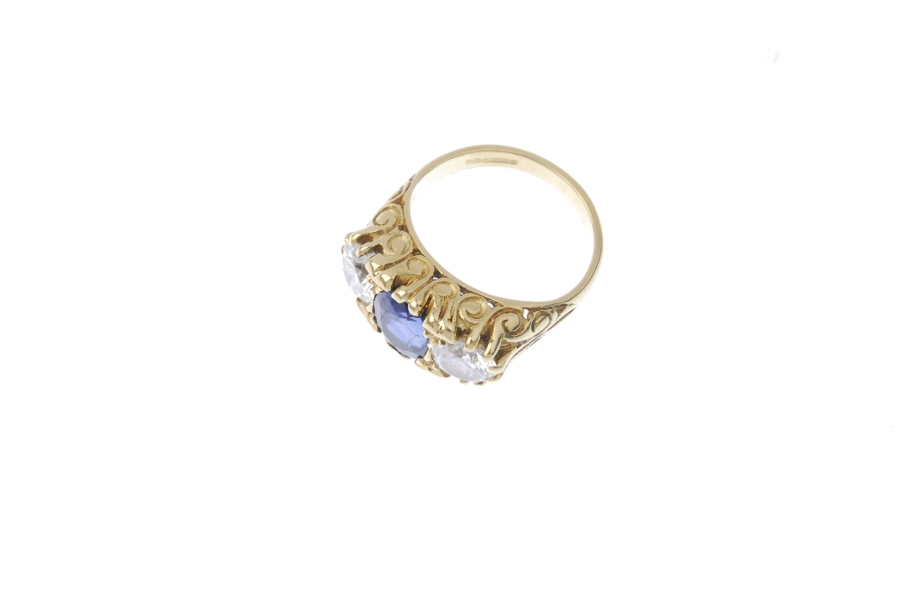 An 18ct gold sapphire and diamond three-stone ring. The oval-shape sapphire, between brilliant-cut - Image 2 of 3