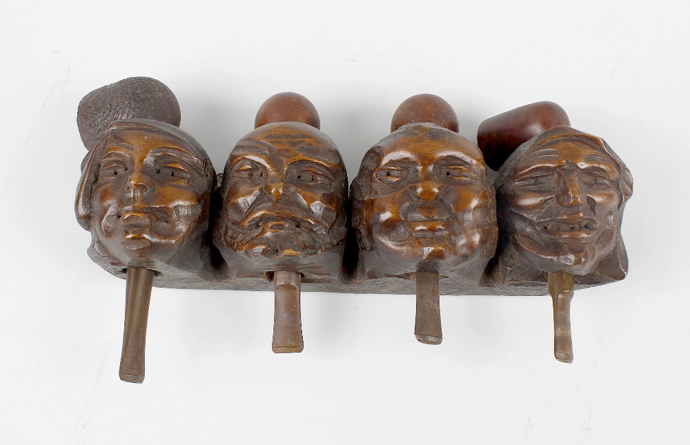 A carved figural pipe rack. Modelled as four grotesque masks each supporting a pipe, 10.75 (27.