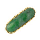 A jade saddle ring. The curved rectangular jadeite cabochon, to the floral embossed and Asian