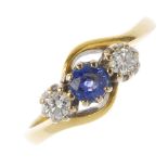 An 18ct gold sapphire and diamond three-stone ring. The circular-shape sapphire, with brilliant-