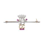 An early 20th century diamond and ruby bar brooch. Designed as a diamond initial 'L' and crown, with