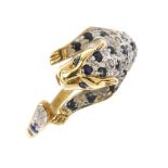 A 9ct gold sapphire and diamond leopard ring. The leopard body and tail crossover terminals, with