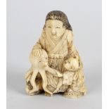 A Japanese ivory netsuke, modelled as a female with long hair seated beside an octopus and child