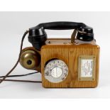 A vintage oak cased, wall hanging telephone, with Bakelite handset, chromed dial and brass bell, the